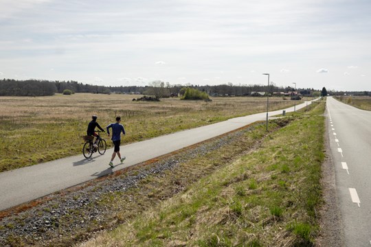 Perseus tränar med sin mor på cykeln bredvid längs landsvägen